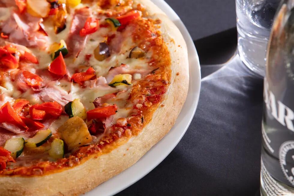 Pizza mit Toppings und Wasser